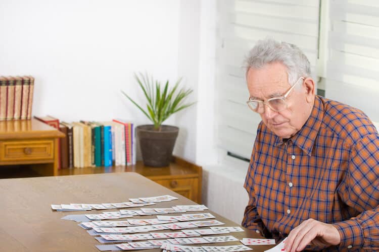 Older man playing solitaire to increase mental stimulation.