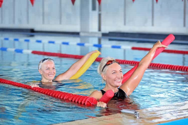 Two senior women participating in a water aerobics class.
