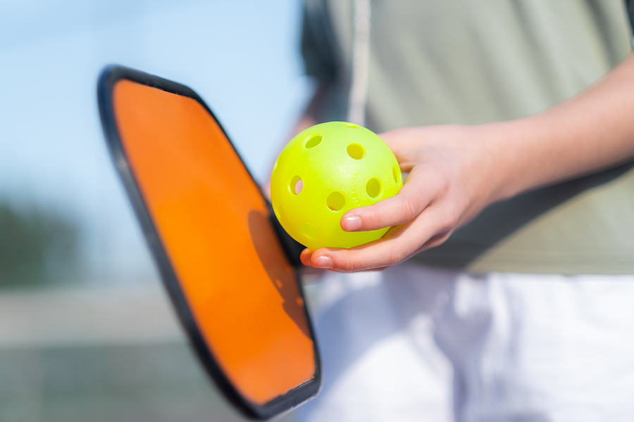 A close-up shot of a pickleball paddle and ball