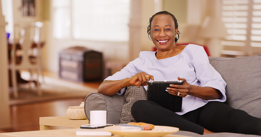 Senior woman sitting on a couch using a tablet