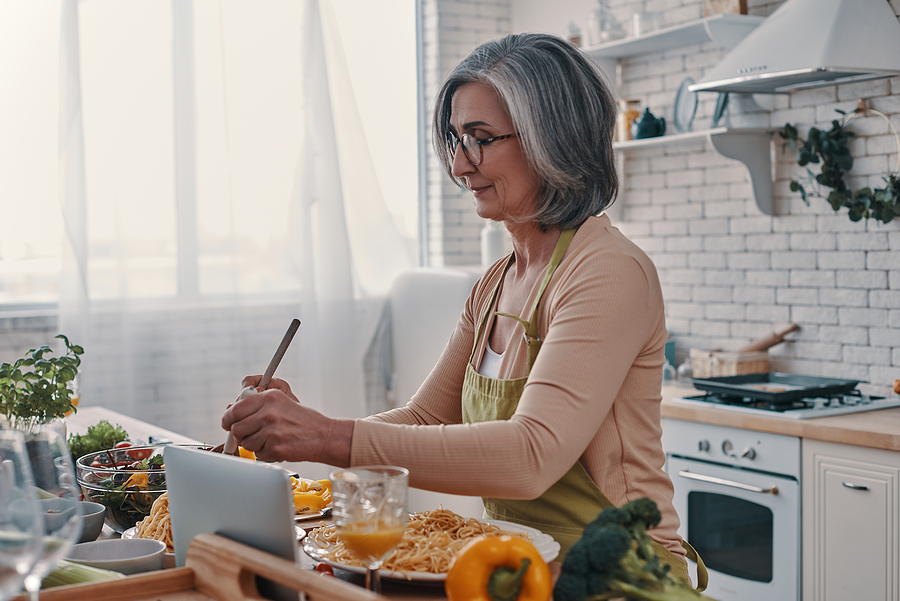 A senior woman cooks in her kitchen.