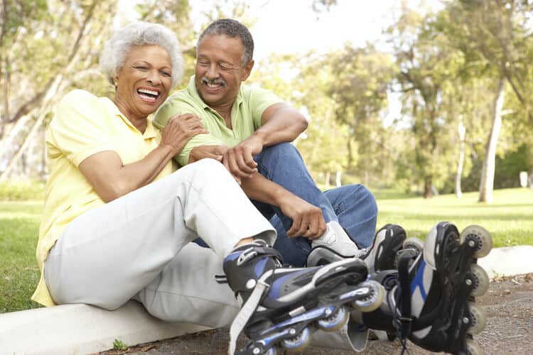 A senior couple enjoys being independent as they rollerblade in the park.
