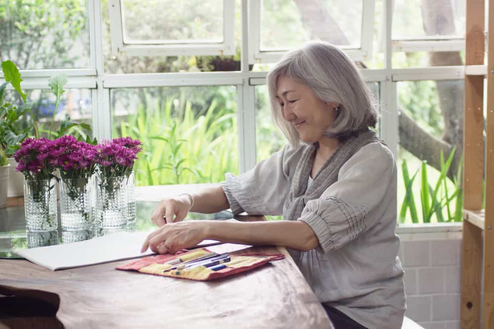 A senior woman sketching flowers in a vase