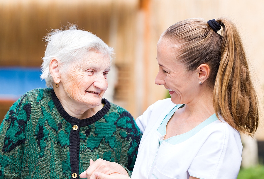 Older woman in a skilled nursing care community smiling at younger woman