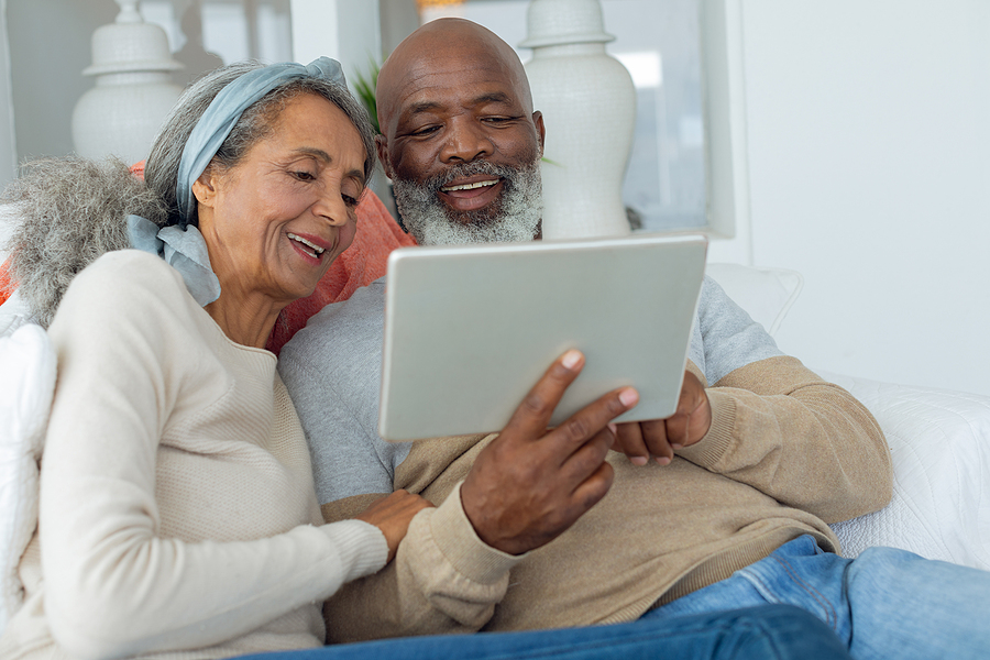 A senior couple sits looking at apartment floor plans together