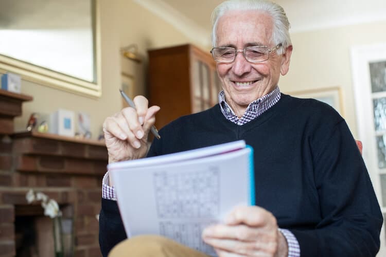 Senior man keeping his brain healthy by completing a crossword puzzle.
