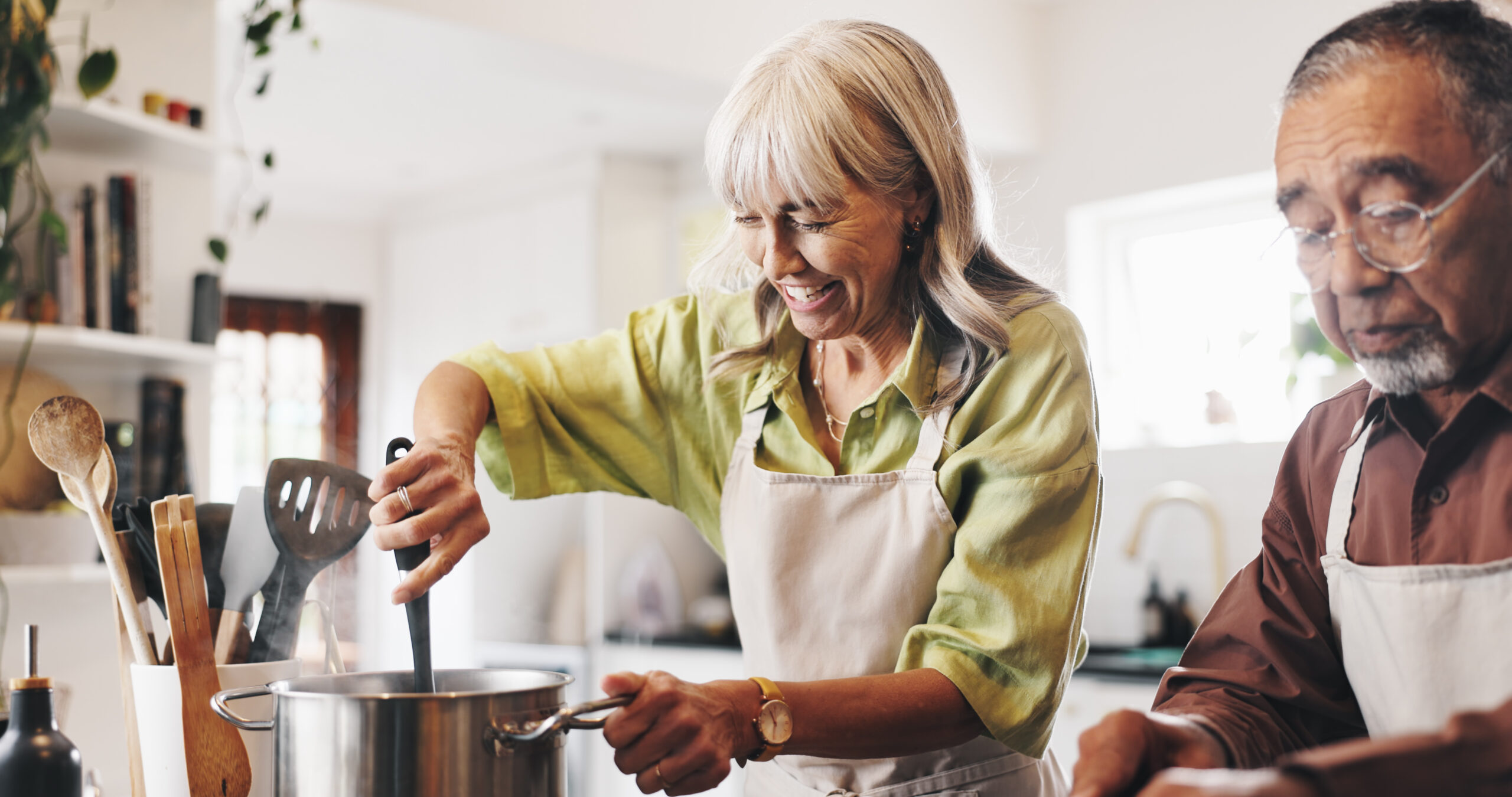 An older couple smiling while cooking together